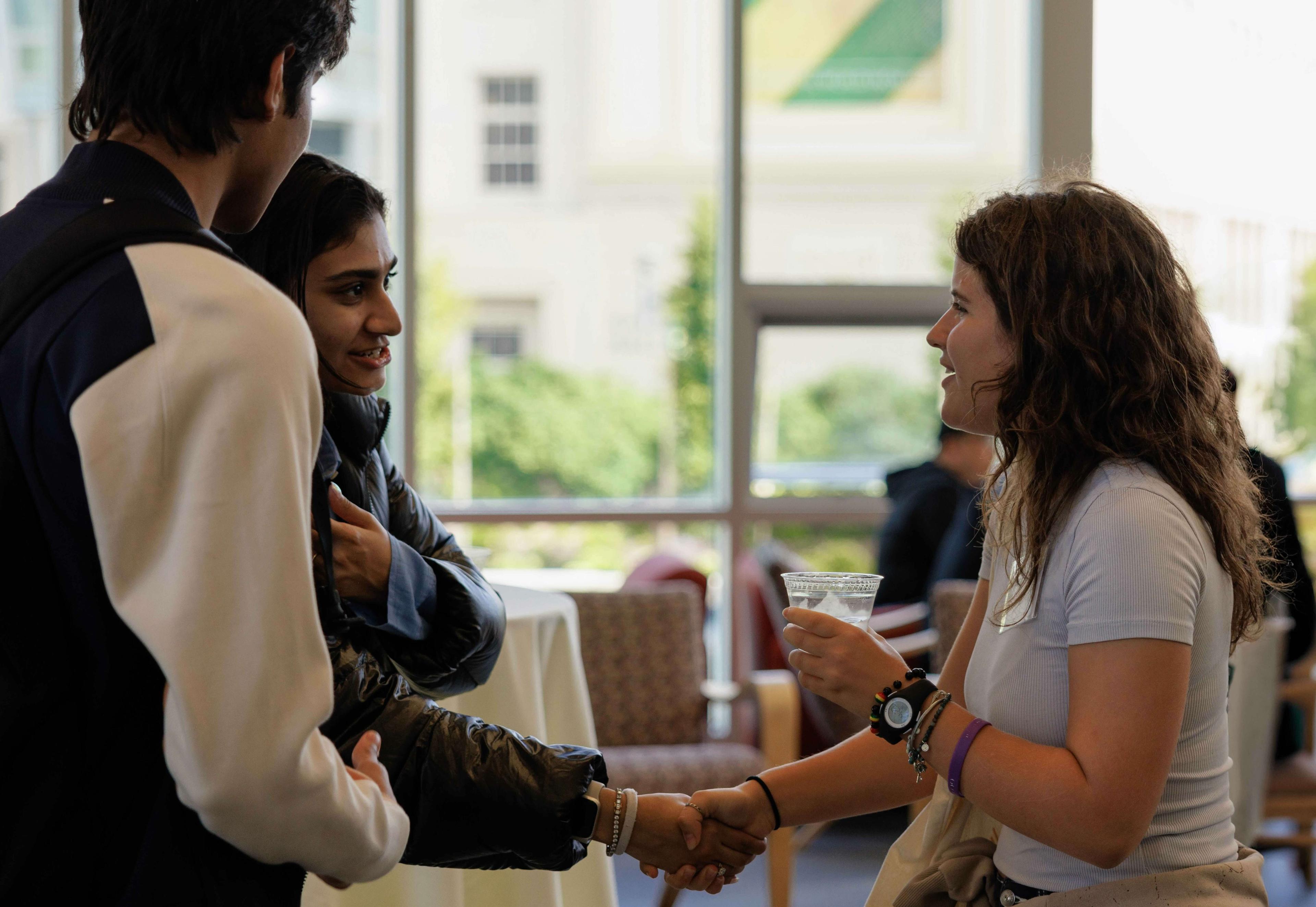 Three USF international students smiling and meeting each other.
